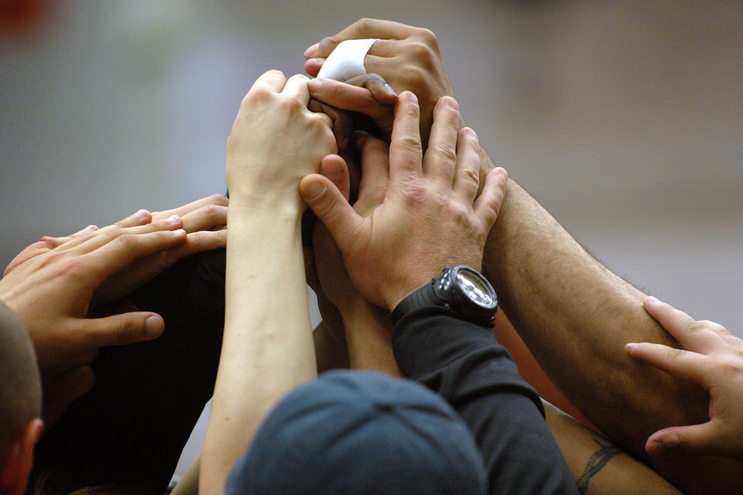 A group of people have their hands together in the air in a group cheer